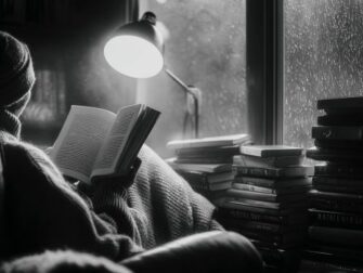 Person liest im Schatten bei Regenlicht in einem Sessel neben Bücherstapeln